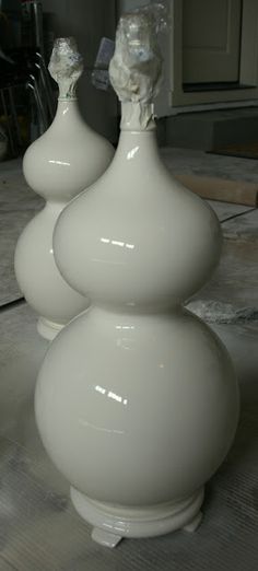 three white vases sitting on top of a table