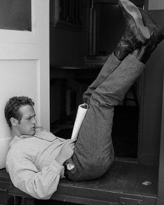 a man laying on the ground with his feet up and holding a book in front of him