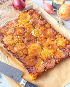 a piece of pizza on top of a cutting board next to garlic and onion slices