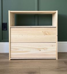 a wooden dresser sitting on top of a hard wood floor next to a green wall