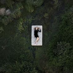 an aerial view of a woman laying on a mattress in the middle of some water