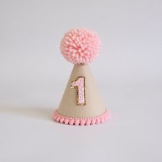 A special little accessory to celebrate a big occasion! Perfect for Cake Smash photoshoots or that special touch to a 1st Birthday outfit, costumes and dress ups.  DETAILS ♕  1 x 100% Merino Wool Felt Party Hat. Finished with mini pom trim, number of choice and wool Pom.  (any number available, not just for 1st Birthdays. Please select number) Elastic comes attached to wear around back of head. ♕ Matching "One" cake topper to go with handmade hat available. Select this option in the drop down to Fun Costume Hats For Birthday, Fun Adjustable Birthday Party Supplies, Fun Birthday Party Hat Supplies, Adjustable Mini Hats With Round Crown For Birthdays, Adjustable Mini Hats With Round Crown For Birthday, Fun Pink Birthday Costume Hats And Headpieces, Adjustable Round Crown Mini Hats For Birthday, Cute Adjustable Mini Hats For Birthday, Whimsical Adjustable Mini Hats For Birthdays