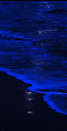 the moon shines brightly in the dark blue sky over the water at the beach