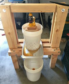 a bucket is sitting on the back of a wooden stand with a bottle in it