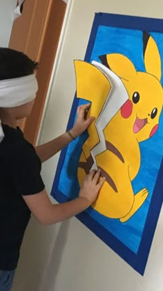 a woman cutting up a paper pikachu art piece on the side of a wall