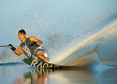 a man riding skis on top of a lake next to a wave in the ocean