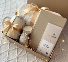 an open box with candles, tea lights and a gift bag in it on a bed