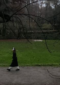 a woman walking across a lush green park