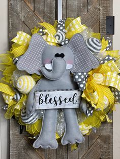 a yellow and gray wreath with an elephant holding a sign that says, blessed on it