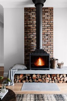 a wood burning stove in a living room next to a pile of firewood on a rug