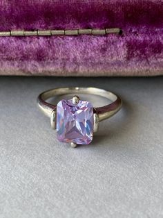 Pretty sparkly pale lilac stone sterling silver solitaire ring. Circa 1980s - 1990s. I was really taken by the unusual color of this one - it's a spin on the classic emerald-cut stone but with a unique pale sparkly lavender stone. Lovely! Tested the stone with my gemstone tester at home and didn't get a conclusive result. Stone measures approximately 8 x 10 mm with a flat table and sharp faceting. Simple, classic and feminine setting.  Solid sterling silver, signed 925 inside band. Size 7.5 - 7. Lilac Ring, Lilac Stone, Table Plate, Lavender Stone, Pale Lilac, Local Jewelry, Floral Jewellery, Lilac Purple, Pretty Rings