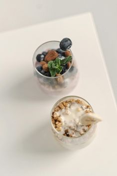 two cups filled with different types of food on top of a white table next to each other