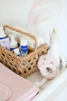 a basket filled with baby items sitting on top of a white dresser next to a stuffed animal