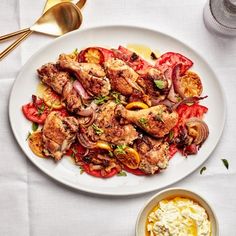 a white plate topped with meat and veggies next to a bowl of sauce