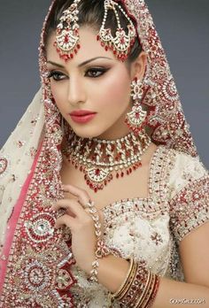 a beautiful woman in a bridal outfit with jewelry on her head and veil over her face