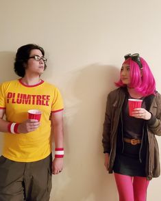 two people standing next to each other with pink hair and one holding a cup in his hand