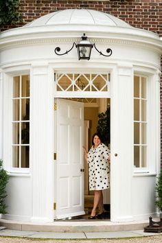 a woman standing in front of a white door with black polka dots on her dress