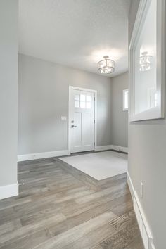 an empty room with white walls and wood floors