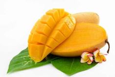 a mango fruit cut in half and placed on top of a green leaf with flowers