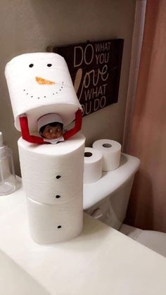 a toilet paper snowman is sitting on top of the toilet