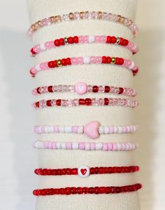 a stack of bracelets with hearts and beads on display in front of a white wall