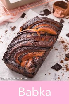 a loaf of chocolate cake sitting on top of a white counter next to a pink sign