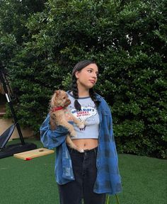 a woman holding a dog in her arms while standing next to a tee ball field