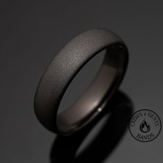 a ring with a black coating is shown on a dark surface, and the logo for flames