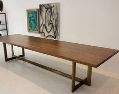 a wooden table sitting in the middle of a room next to a shelf with vases on it