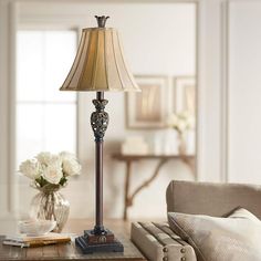 a living room with a couch, table lamp and flowers in vases on the coffee table