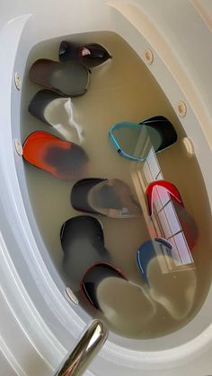 a white toilet bowl filled with water and lots of different colored shoes in it's lid