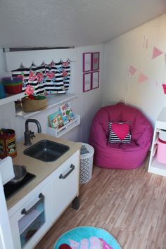 a small child's playroom with pink furniture and accessories