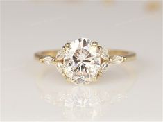 an oval cut diamond with three pear shaped diamonds on the band and shoulders, set in 18k yellow gold