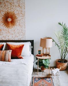 a bedroom with a bed, lamp and plants on the side table in front of it