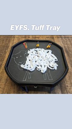 a black tray with white stuff on it and the words eyfs tuff tray