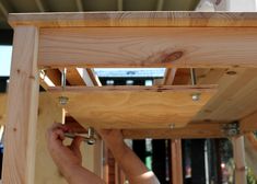 a person is working on the underside of a wooden structure with screws and nails