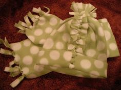 a green and white polka dot hat with ruffles on the side, sitting on a brown blanket