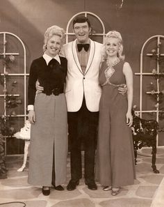 an old photo of three women and a man in formal wear standing next to each other