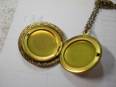 "This is a 1\" solid brass locket with a beautiful ornate brass charm on the face. Locket opens to hold two 3/4\" photos. You choose the chain length in the drop down menu above. The locket and the charm on the top are both vintage 1960's stock and I have created a one of a kind locket using both components. The perfect necklace for layering! A nice dainty size. The chain is also solid brass and you may choose your preferred length in the drop down menu above. I offer quick shipping and all pack Antique Gold Medallion Locket Necklace With Intricate Design, Handmade Antique Gold Medallion Locket Necklace, Handmade Antique Gold Brass Locket Necklace, Victorian Brass Locket Necklace With Vintage Charm, Antique Gold Medallion Locket Necklace In Bohemian Style, Gold Brass Round Pendant Locket Necklace, Antique Gold Pendant Locket With Intricate Design, Bohemian Gold Locket Necklace With Vintage Charm, Gold Brass Locket Necklace With Round Pendant