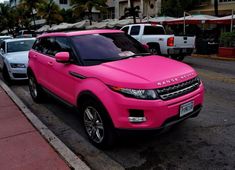 a pink range rover parked on the side of the road in front of some cars