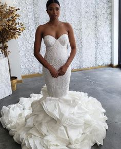 a woman in a white wedding dress standing with her hands on her hips and looking at the camera