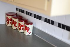 four red and white canisters sitting on top of a counter in a kitchen