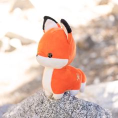 a stuffed fox sitting on top of a rock