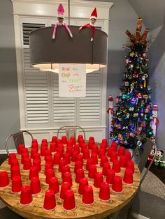 a table with red cups on it in front of a christmas tree and elf decorations