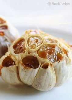 two garlic shells on a white plate with the words how to roast garlic