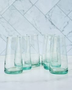 four glasses are lined up on a marble counter