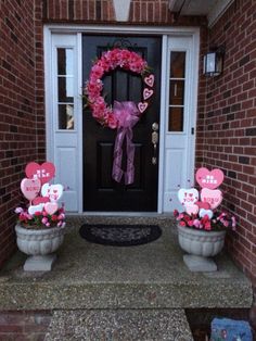 two planters with flowers and hearts are on the front step of a house, decorated for valentine's day