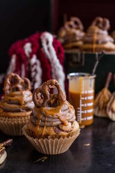 two cupcakes with chocolate frosting and pretzels on top are sitting on a table