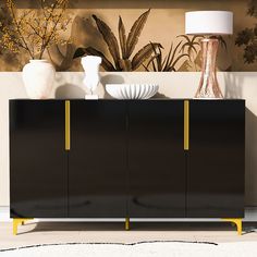 a black cabinet with yellow handles and two white plates on it, in front of a wall with potted plants