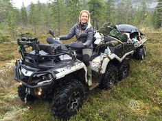 a woman sitting on an atv in the middle of a field with trees behind her